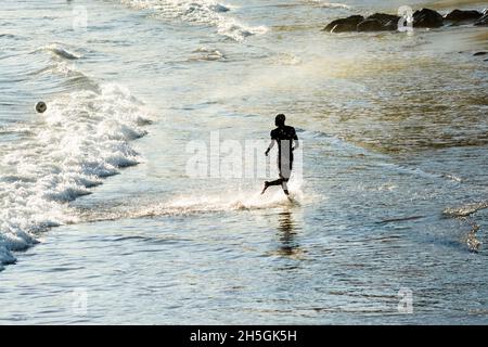 Homme sortant lentement de la mer de la plage d'Ondina après avoir été baigné.Salvador Bahia Brésil. Banque D'Images