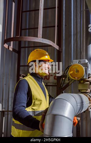 Homme enjoué dans un casque de sécurité travaillant en usine Banque D'Images