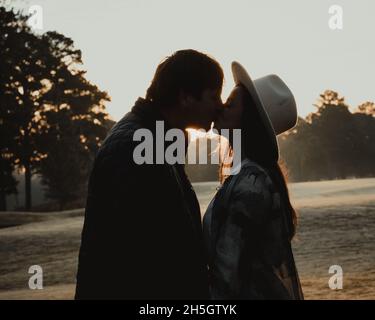 couple embrassant au lever du soleil - silhouettes noires contre un lever de soleil jaune et blanc Banque D'Images