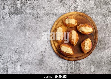 Croissants avec fromage et saucisse sur une planche à découper ronde en bois sur fond gris foncé.Vue de dessus, plan d'appartement Banque D'Images