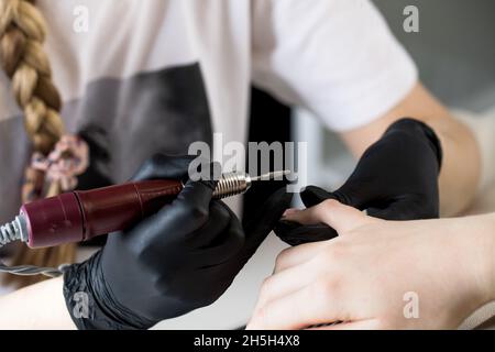 Un manucuriste enlève le gel vernis des ongles à l'aide d'une fraise.Gros plan sur la manucure de quincaillerie.Revêtement de la gomme laque sur les ongles Banque D'Images