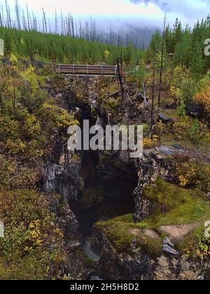 Vue imprenable sur une passerelle en bois qui s'étend sur un ravin profond et étroit à Marble Canyon, dans le parc national Kootenay, en Colombie-Britannique, au Canada, le jour de la brume. Banque D'Images