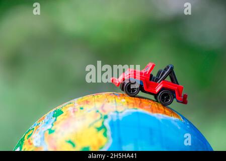 Une voiture sur le globe sur fond vert.Jouet de voiture miniature sur le globe.Concept de voyage Banque D'Images