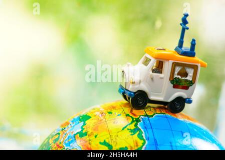 Une voiture sur le globe sur fond vert.Jouet de voiture miniature sur le globe.Concept de voyage Banque D'Images