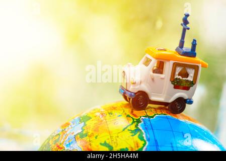 Une voiture sur le globe sur fond vert.Jouet de voiture miniature sur le globe.Concept de voyage Banque D'Images