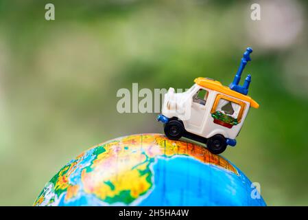 Une voiture sur le globe sur fond vert.Jouet de voiture miniature sur le globe.Concept de voyage Banque D'Images