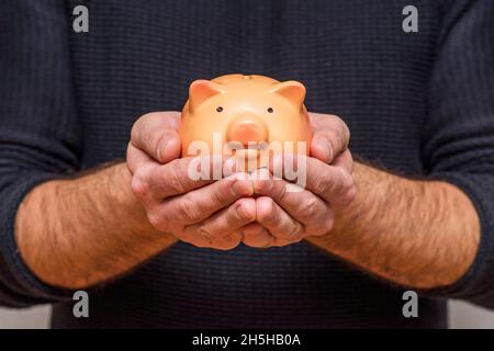 Un homme tenant une banque de Piggy.Homme tenant une banque de porc dans ses mains, symbole de l'épargne et des bons investissements. Banque D'Images