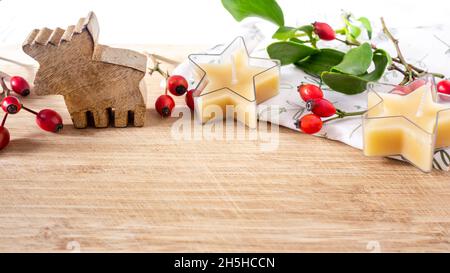 Décoration pour la table de Noël petit élan en bois, bougies en forme d'étoile de cire d'abeille, baies de hanche rose.Gros plan. Banque D'Images