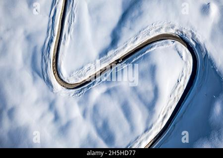 Voiture voyageant sur la route en forme de S dans les montagnes enneigées d'en haut, vue aérienne, Dolomites, Italie Banque D'Images