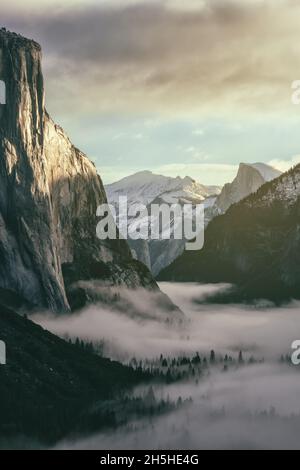 Le soleil du matin se reflète sur le El Capitan, avec vue sur le Half Dome Peak, tandis que le faible brouillard couvre la vallée en contrebas, parc national de Yosemite, CA, Etats-Unis. Banque D'Images