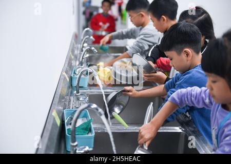 (211110) -- FOSHAN, le 10 novembre 2021 (Xinhua) -- les élèves lavent les plats pendant le cours de cuisine au centre de formation Little Chef de l'école primaire de Xishan, dans le district de Shunde de Foshan, dans la province de Guangdong, dans le sud de la Chine, le 9 novembre 2021.L'école primaire de Xishan à Shunde a mis en place un centre de formation Little Chef depuis septembre de cette année sur son campus scolaire en collaboration avec l'école de formation professionnelle Shunde Fengchu, offrant aux élèves un cours de cuisine de 45 minutes après l'école chaque jour.Les instructeurs de cuisine professionnels, avec les enseignants de l'école, donnent des cours de cuisine adaptés f Banque D'Images