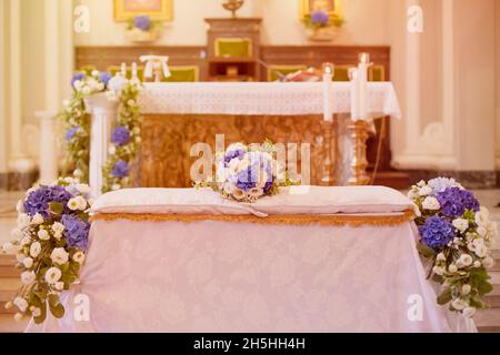 Bouquet de mariée coloré composé de fleurs blanches et bleues sur des coussins au-dessus du banc de mariage devant l'autel de l'église Banque D'Images