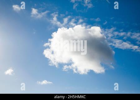 Un seul nuage de fleecy, ainsi que quelques nuages de plumes, ornent le ciel bleu dans des vents forts Banque D'Images