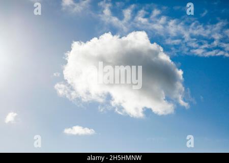 Un seul nuage de fleecy, ainsi que quelques nuages de plumes, ornent le ciel bleu dans des vents forts Banque D'Images