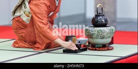 Une femme dans un kimono s'agenouillant sur un tatami prépare le thé lors d'une démonstration d'une cérémonie traditionnelle du thé japonais.L'image de gros plan. Banque D'Images