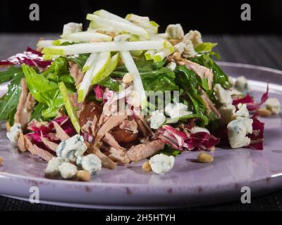 salade avec filet de dinde tiré, fromage bleu, laitue verte fraîche et poire sucrée sur une assiette, photo horizontale en gros plan Banque D'Images