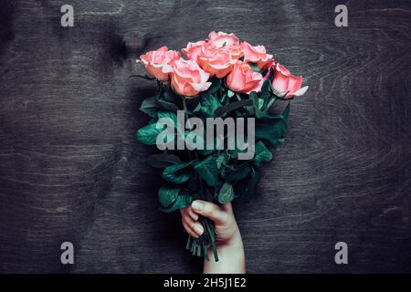 Les mains des femmes tiennent un bouquet romantique de roses rose tendre sur fond de bois carte florale de vacances anniversaire, mariage, bonne Saint-Valentin, mère, enseigner Banque D'Images