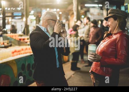 Joyeux couple senior s'amusant avec un appareil photo vintage sur le marché de Londres - attention douce sur le visage féminin Banque D'Images