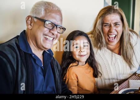 Bonne fille latine ayant plaisir à manger avec ses grands-parents à la maison - Focus sur le visage de petit enfant Banque D'Images