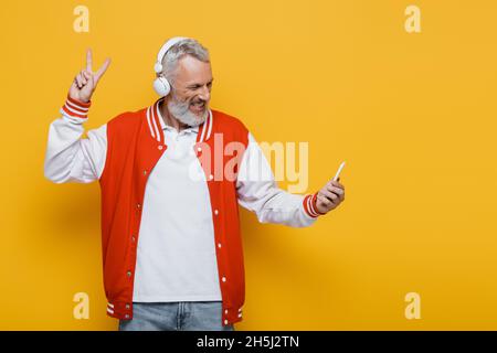 heureux homme d'âge moyen dans un casque qui prend le selfie tout en montrant une affiche sur le jaune Banque D'Images