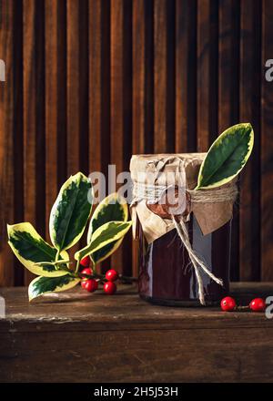 Confiture de fruits maison dans un pot décoré avec du papier de grunge, du sceau de cire et des feuilles vertes de houx comme petit cadeau de Noël. Concept d'idées de cadeau de cuisine Banque D'Images