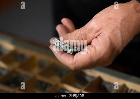 Lettres alphabet blocs en métal dans la main Old Man Banque D'Images