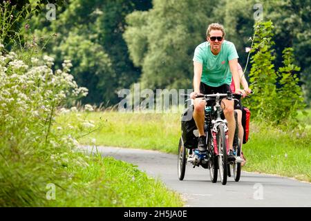 Un homme faisant du vélo sur un sentier qui mène à travers la prairie Allemagne chemin de Saxe dans la nature Banque D'Images