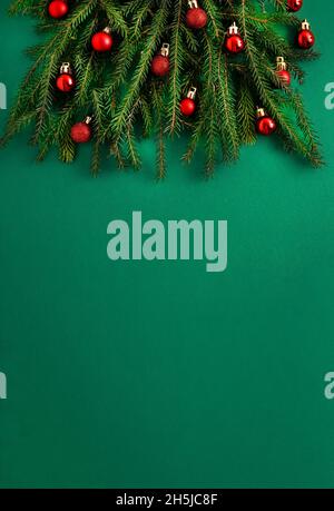Arbre de Noël en branches de conifères vertes sur fond vert.Arrière-plan de Noël avec emplacement pour le texte.Concept de vacances de Noël.Jouets de balle.Boules rouges Banque D'Images