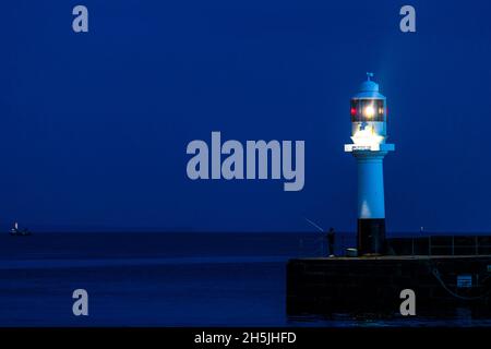 Garçon pêchant sur la jetée à l'entrée du port de Penzance. Banque D'Images