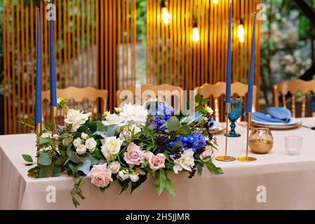 Présidium de mariage, table de banquet pour les jeunes mariés avec fleurs, verdure, bleu et or.Arrangement de fleurs luxuriantes sur la table de mariage.Lumière brillante Banque D'Images