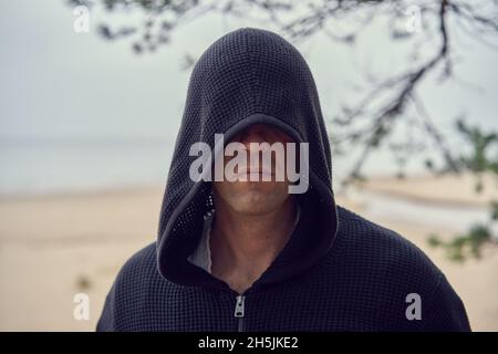 Une personne dans un sweat à capuche noir ressemble à un assassin.Cosplay.Chaussures de mer à l'arrière-plan.Photo de haute qualité Banque D'Images