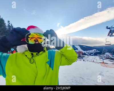 joyeux homme en tenue de ski avec chapeau de noël rouge père noël en hiver, les montagnes de la colline de l'espace de copie Banque D'Images