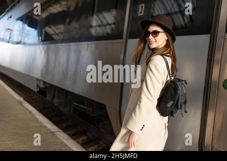 Beau voyageur avec sac à dos sur la plate-forme de la gare. Jeune femme près du train Banque D'Images