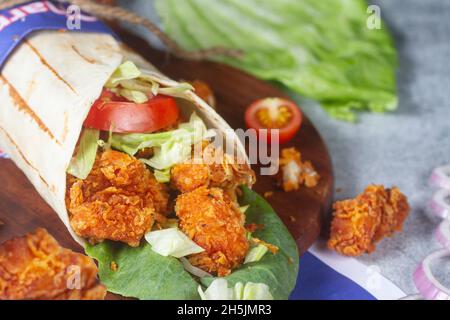 Rouleau de pop-corn au poulet frais avec tomates fraîches, salade, fromage et oignons isolés sur fond bleu vif.Mise au point du côté view.selective Banque D'Images