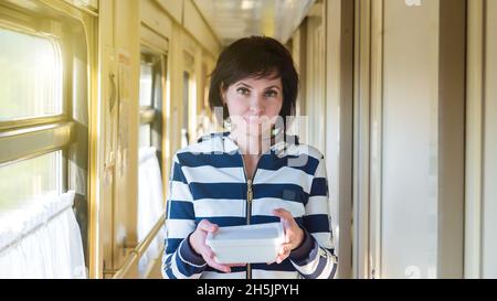 La brunette descend le couloir du train transportant une plaque chaude de nourriture dans ses mains et peur de se brûler. Banque D'Images