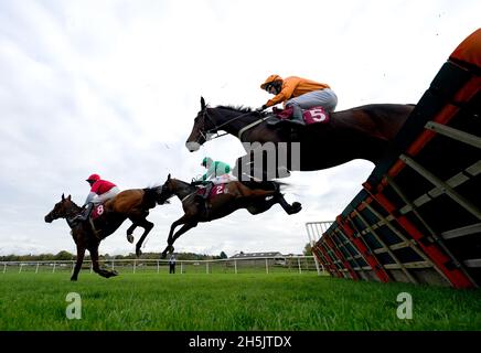 Saint Segal, monté par le jockey Chester Williams (à droite, silks orange), se met à franchir un obstacle sur le chemin de gagner les dix à suivre à l'obstacle tote.co.uk Juvenile Maiden à l'hippodrome de Bangor-on-Dee.Date de la photo: Mercredi 10 novembre 2021. Banque D'Images