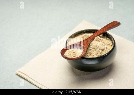 poudre de racine de maca dans un petit bol en céramique avec une cuillère à café en bois - super nourriture Banque D'Images