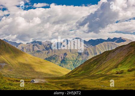 Un camion monte sur la route jusqu'au Hatcher Pass Lodge et à la mine d'or de la monnaie, avec la toundra de couleur automnale et les monts Talkeetna en arrière-plan,... Banque D'Images