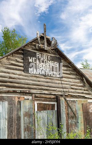 Un panneau pour le 'Ruby accueille le Marathon 800' est exposé sur une ancienne cabane en rondins en été, Ruby, intérieur Alaska, États-Unis Banque D'Images