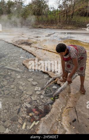 Femme cuisant des ignames dans les sources thermales Dei Dei sur l'île de Fergusson, aux îles d'Entrecasteaux, en Papouasie-Nouvelle-Guinée Banque D'Images
