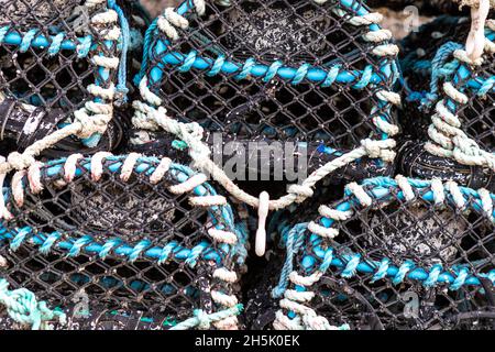 Pots de homard et boîtes à poissons empilés à l'extérieur d'une maison à poissons.Newlyn Harbour, Cornwall.ROYAUME-UNI Banque D'Images