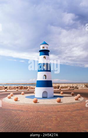 Beau petit phare méditerranéen en bleu et blanc lors d'une belle journée ensoleillée. Banque D'Images