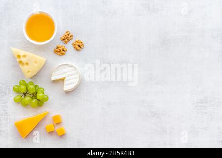 Divers types de fromage avec miel et raisins. Vue de dessus de la pose à plat Banque D'Images