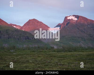 La neige couvrait Akka, le massif de la montagne Ahkka avec glacier et bouleau, rose rouge coloré par la lumière du coucher du soleil.Paysage suédois de la Laponie à Padjelantaleden Banque D'Images