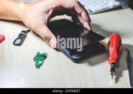 L'homme est la réparation d'un téléphone mobile. Banque D'Images