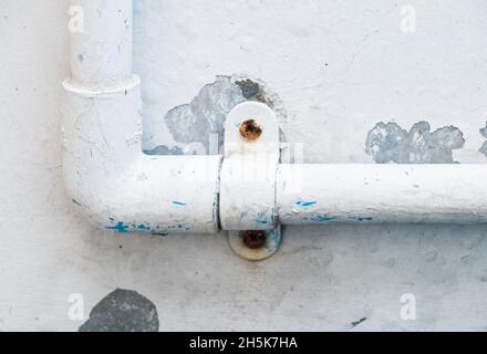 Le tuyau en PVC avec le collier en plastique pour le système d'alimentation en eau dans la maison urbaine près du mur en béton blanc, vue avant de l'espace de copie. Banque D'Images