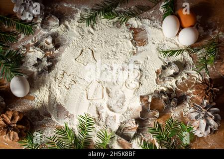 Moules métalliques de Noël pour biscuits au gingembre sur une table en bois avec de la farine.Le concept de la cuisson au curly festive.Farine dispersée, œufs, brindilles d'épinette, cônes Banque D'Images