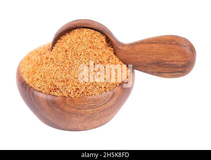 Sucre de noix de coco isolé sur fond blanc.Faire revenir le sucre de noix de coco non raffiné dans un bol et une cuillère en bois. Banque D'Images