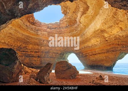 Formations rocheuses de grès à la grotte de Benagil, intérieur de la grotte de mer le long de la côte océanique de l'Algarve avec lumière du soleil qui brille par une ouverture Banque D'Images