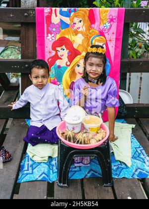 KANCHANABURI THAÏLANDE-DÉCEMBRE 31,2019 : non identifié mon garçon et fille vendent des fleurs et font tanaka powdering service aux touristes sur le bois d'Uttamanuhorn Banque D'Images